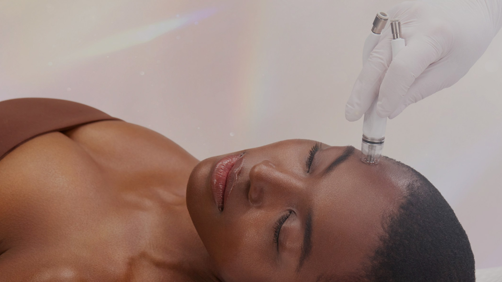 The image shows a person receiving a scalp treatment with a handheld device, possibly at a beauty salon or spa, with a focus on the head and the equipment being used.