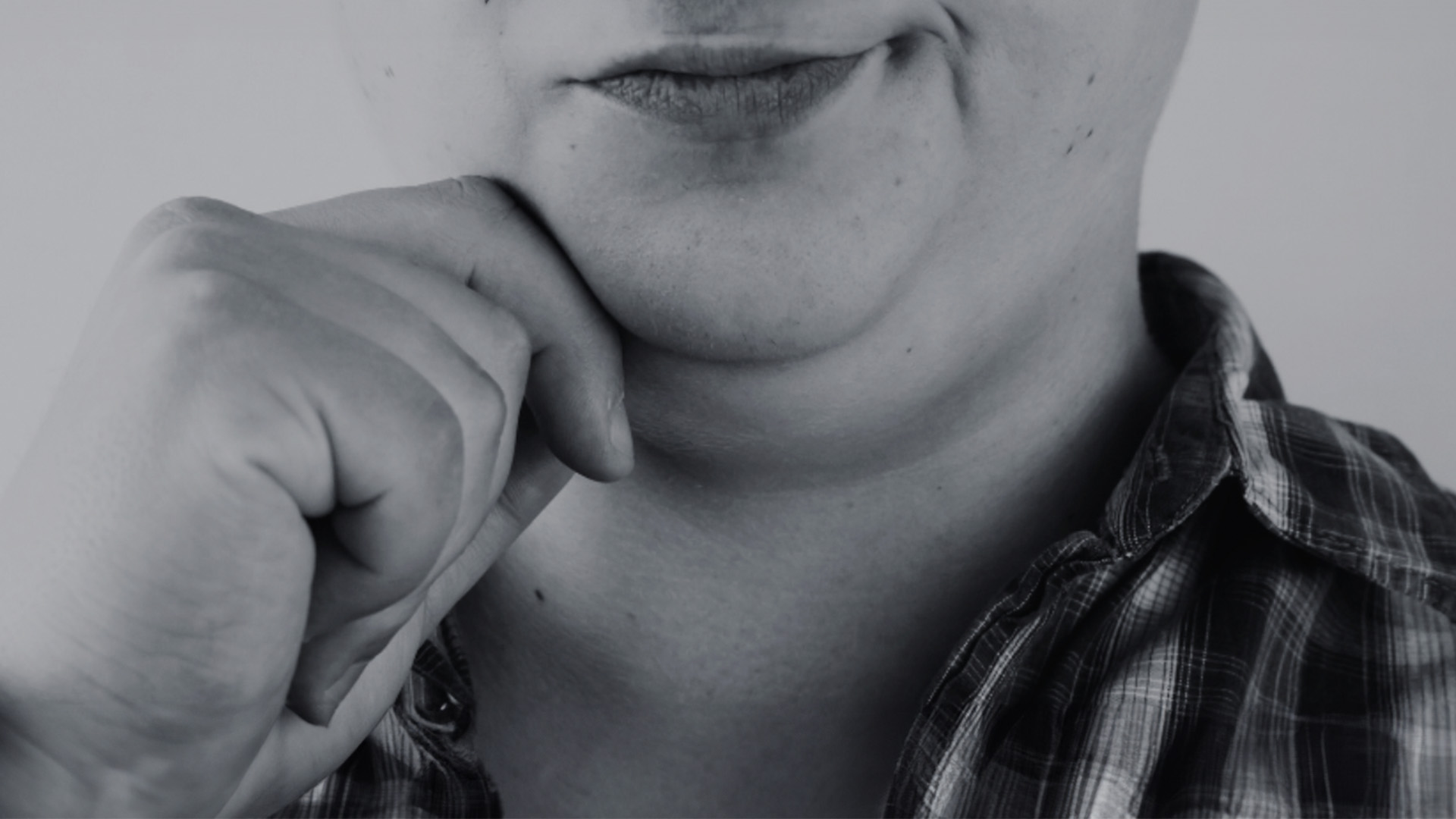 The image shows a person with a neutral expression resting their chin on their hand.