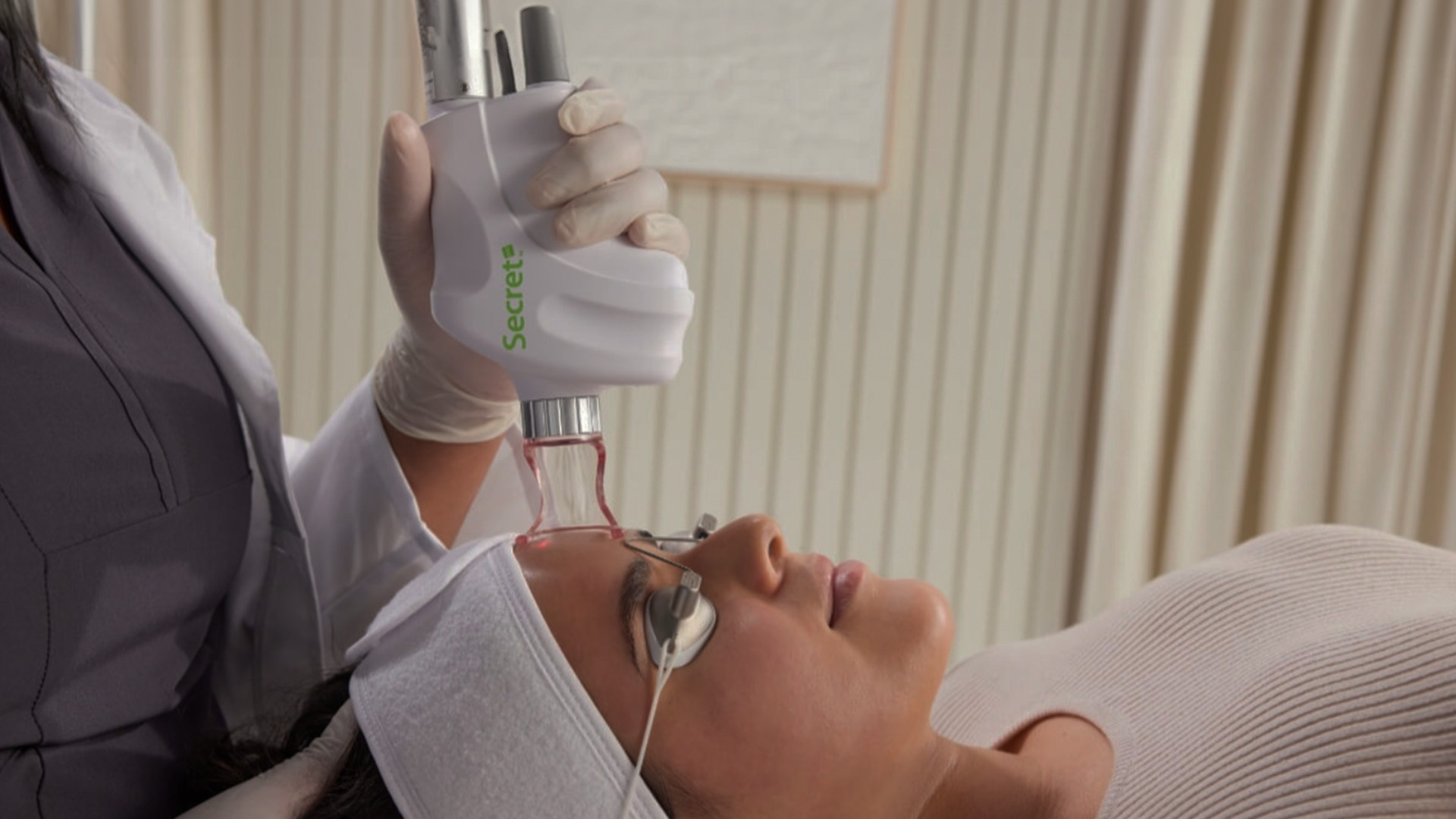 The image depicts a person receiving an eye treatment from a professional using a specialized device, with a focus on precision and care.