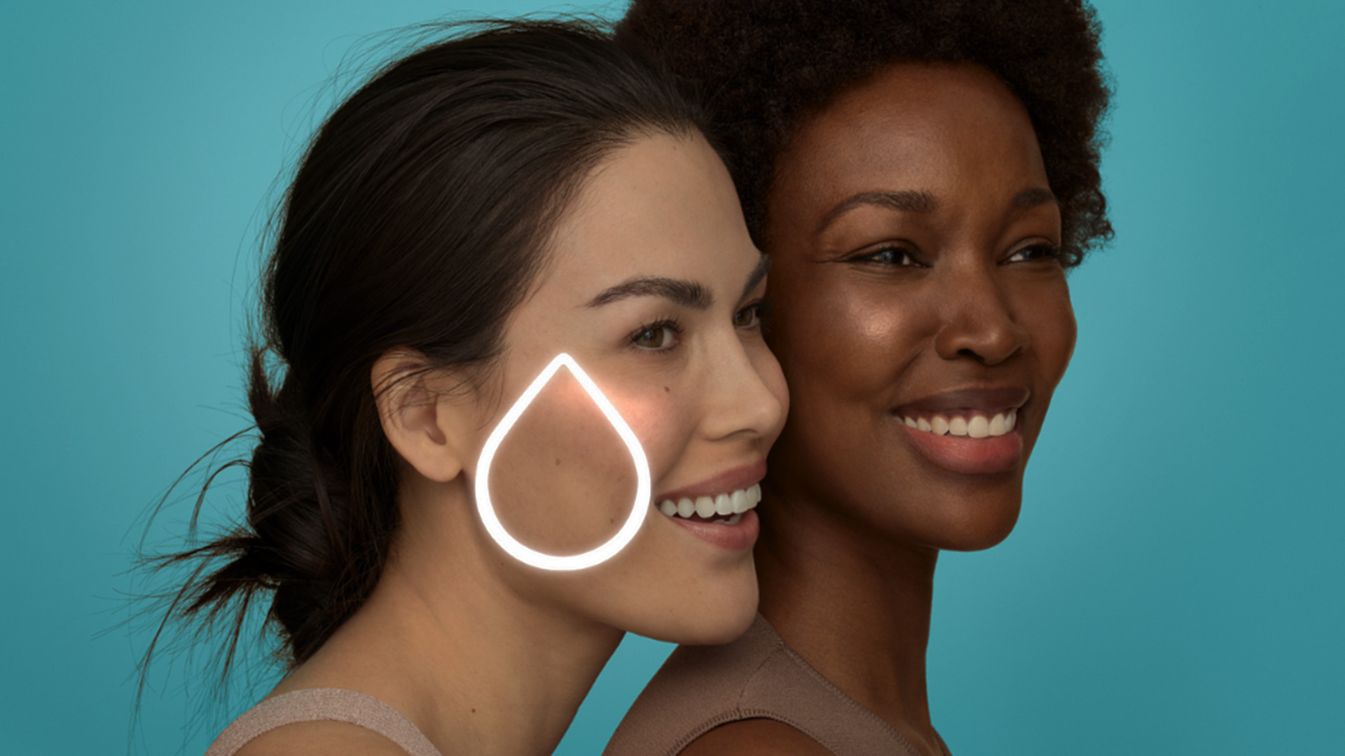 Two women smiling at each other with a cosmetic product visible on their cheeks.