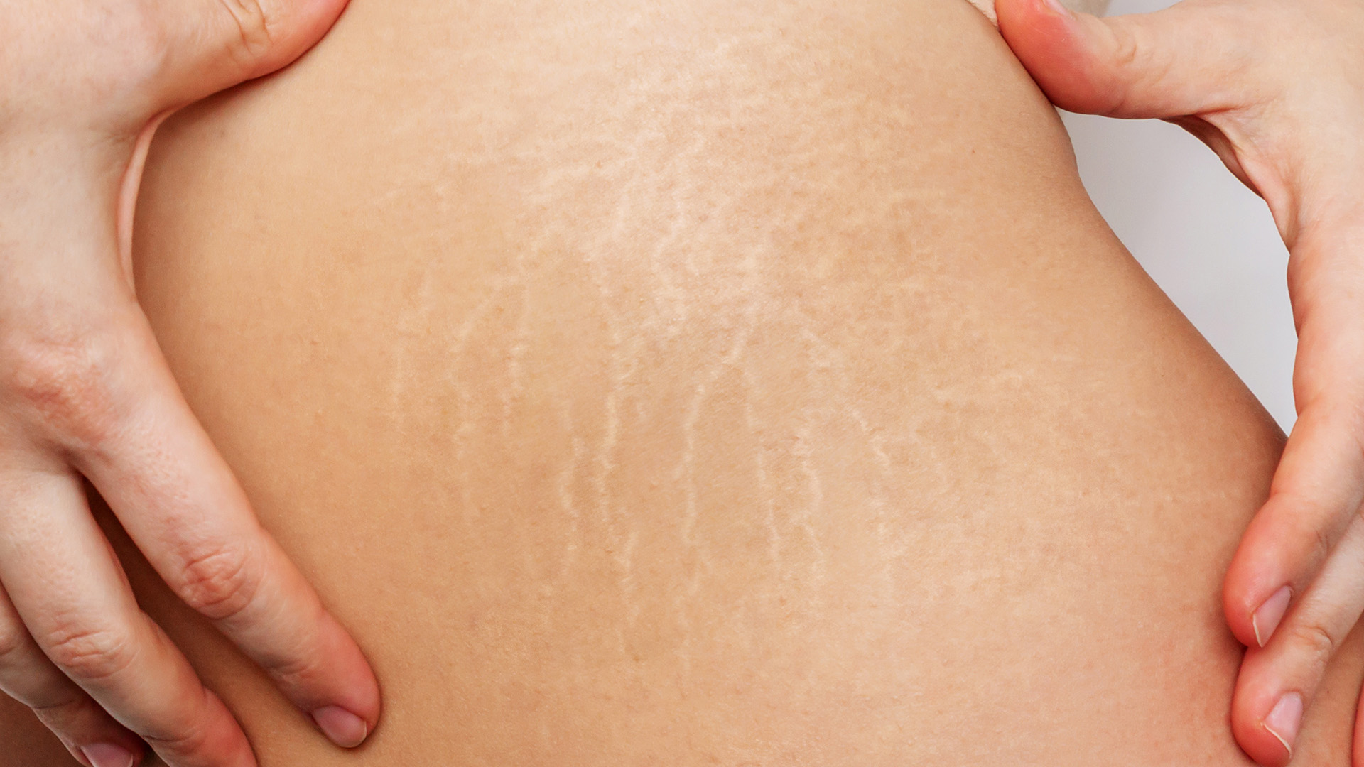 The image shows a close-up view of a person s lower leg with visible tattoo artistry on their skin, while another hand appears to be applying pressure or massaging the area.