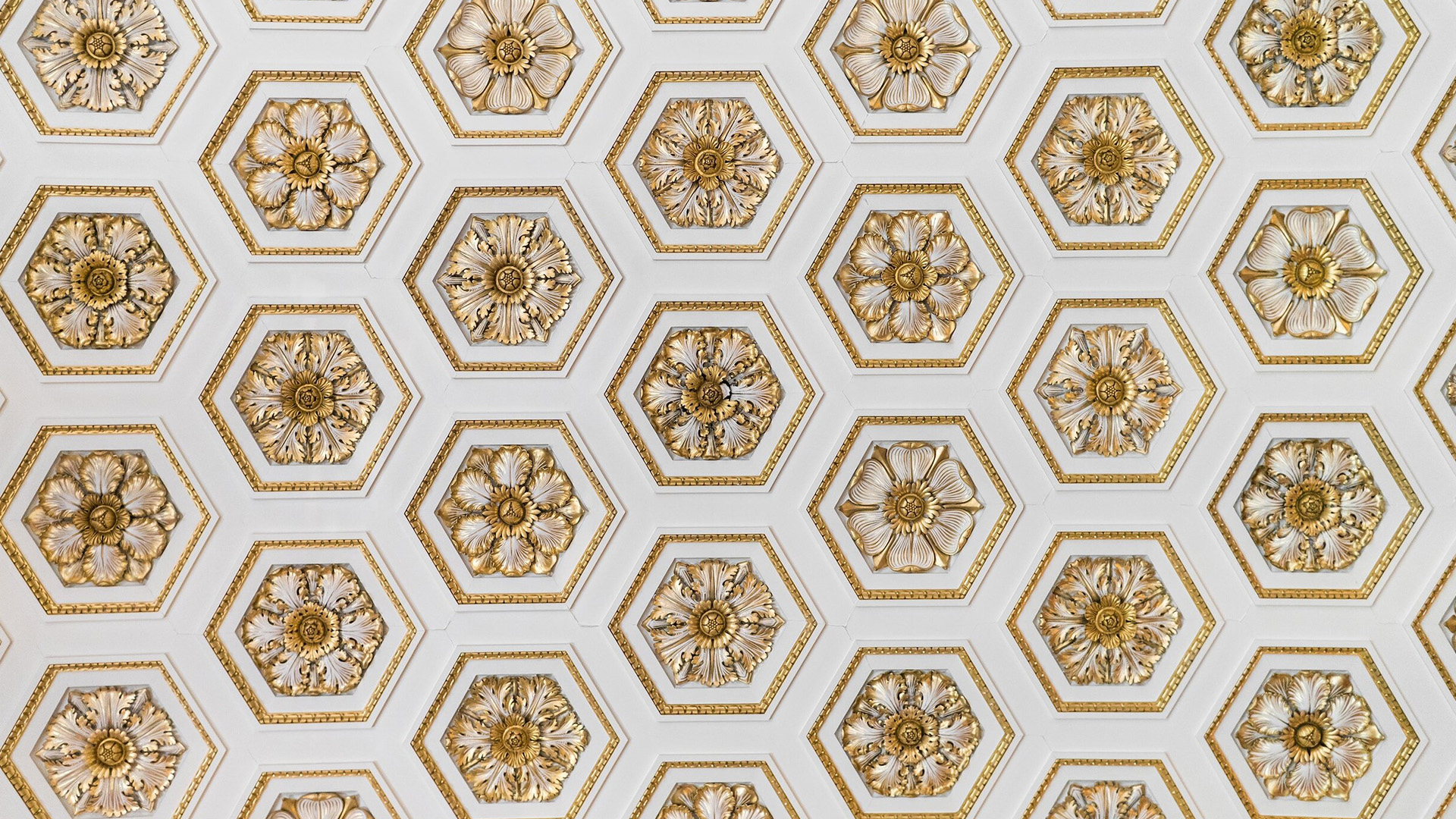 A close-up image of a decorative ceiling with intricate patterns and gold accents.