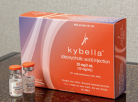 The image shows a box of Kybella injectable cosmetic treatment for double chin reduction, accompanied by two syringes with needles, indicating a medical or healthcare context.