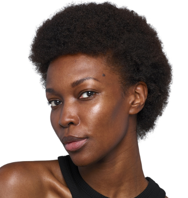 A woman with short curly hair and a black outfit against a white background.