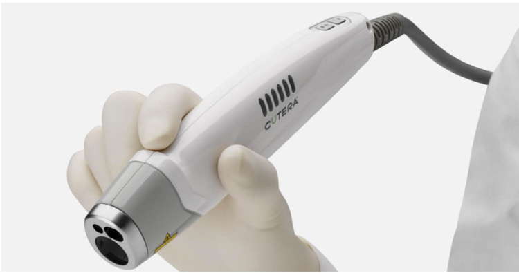 The image shows a handheld device with an attached wand-like tool, being held by a person wearing medical gloves, suggesting a focus on healthcare or beauty technology.