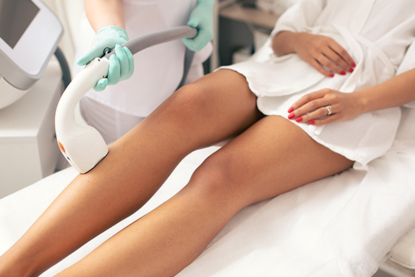 A woman receiving laser hair removal treatment in a professional setting.